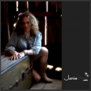 pretty redhead transgender model janie black behind crate in barn in loose denim shirt and cowboy boots cowgirl