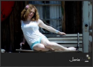 cute redhead transgender model janie black on bench in smalltown america wearing shorts and a flower in her hair